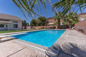View of swimming pool featuring a gazebo, patio surround, a fenced backyard, and a diving board