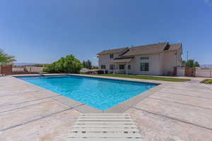 View of swimming pool featuring patio surround, a gate, and a diving board