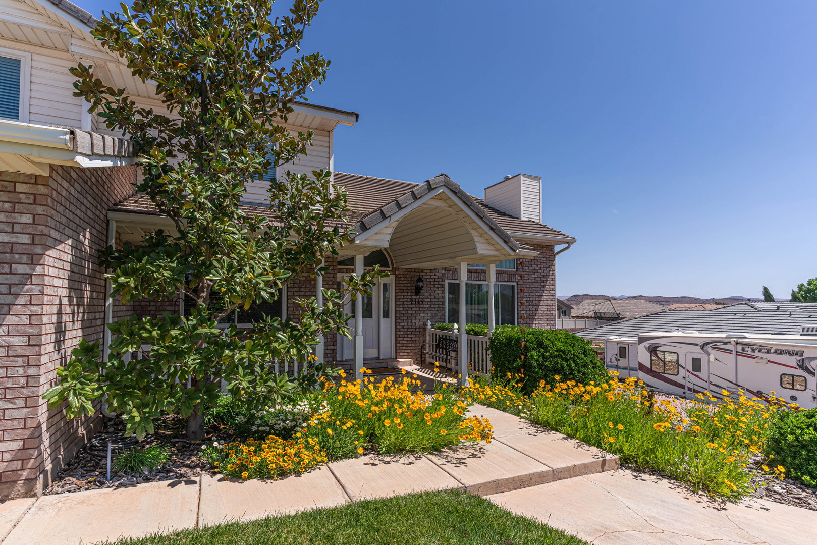 View of front porch with flower garden outlining the walkway.