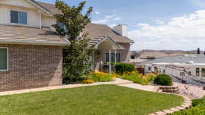 View of front facade featuring brick siding, a front yard, a tiled roof, and a chimney