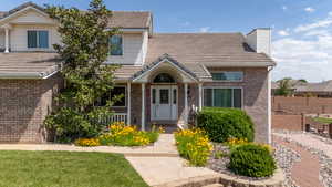 View of front of home featuring brick siding, a chimney, and a tile roof