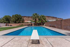 View of swimming pool featuring a gazebo, a diving board, a fenced backyard, and patio surround