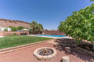View of pool featuring patio surround, a gazebo, a fenced backyard, and an outdoor fire pit