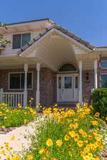 Doorway to property featuring covered porch and brick siding