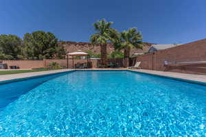 View of swimming pool featuring a gazebo, a fenced backyard, and patio surround