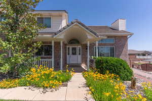 View of front of house with a porch, brick siding, and a chimney