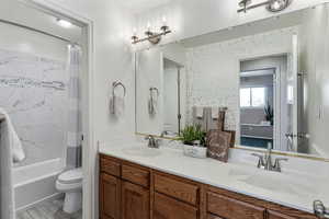 Large upstairs full bathroom with double vanities and and a door separating the toilet/shower area from the sink/vanity area.