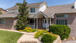 View of front of house with brick siding, a porch, a tile roof, and a front lawn