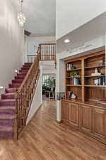 Stairway with wood finished floors, suspended lighting, and a high ceiling