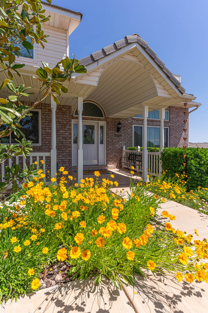 Entrance to home with a covered porch and brick siding