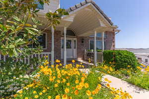 Doorway to property featuring covered porch and brick siding