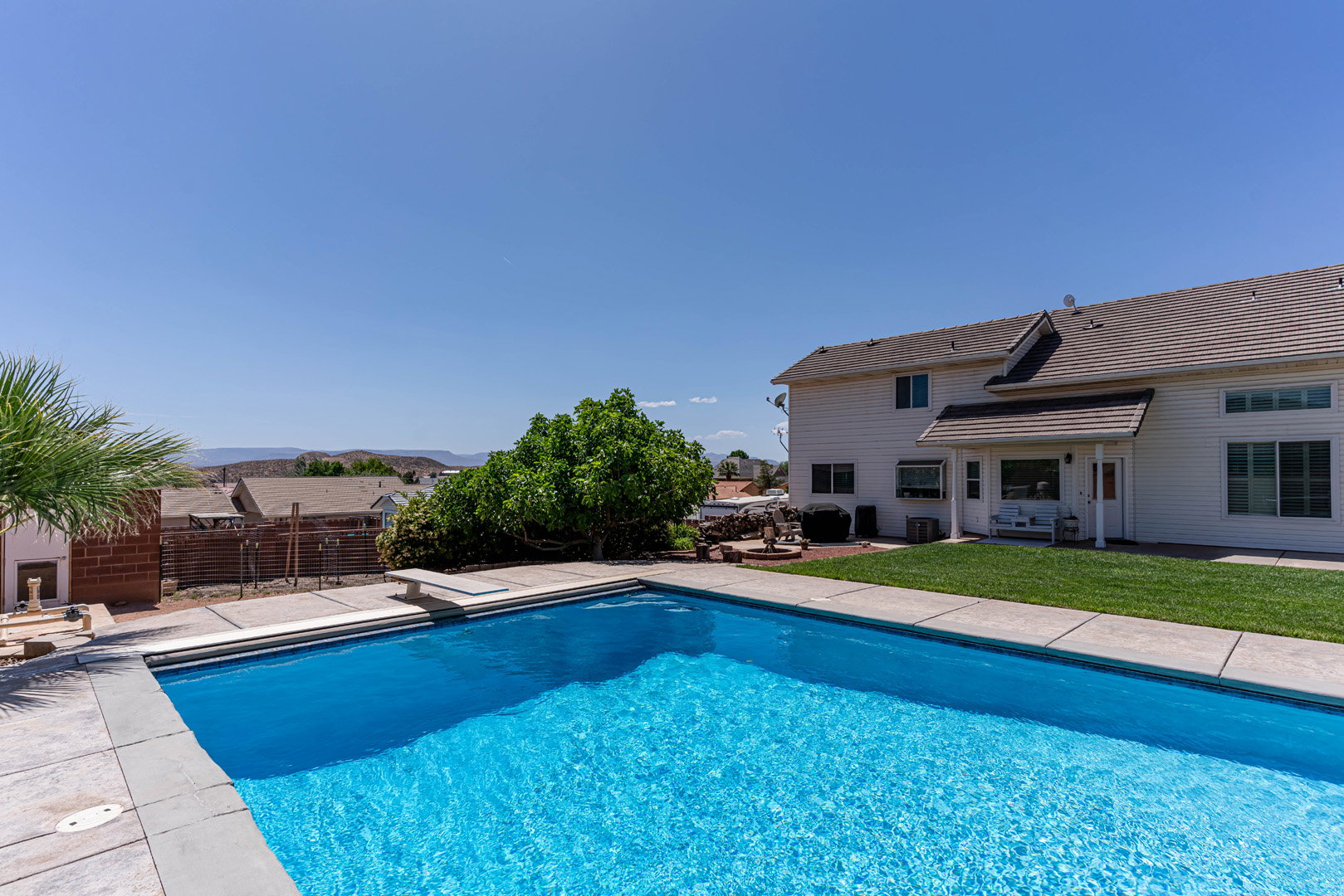 View of swimming pool featuring patio surround, a fenced backyard, and a diving board