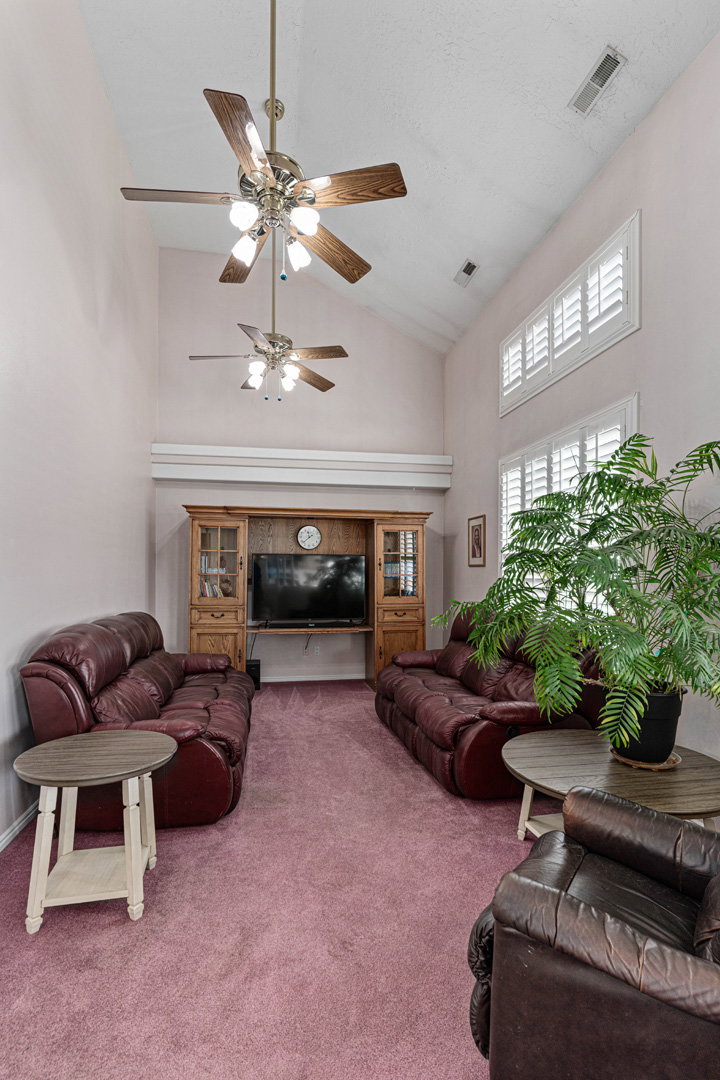 Large living/tv room with windows looking into backyard/pool area.