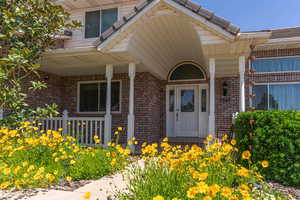 View of exterior entry and front porch with flowers lining the walkway.