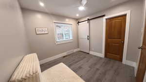 Unfurnished bedroom featuring a barn door, wood finished floors, recessed lighting, and a ceiling fan