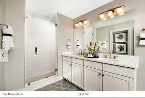 Full bath featuring double vanity, a stall shower, and dark tile patterned flooring