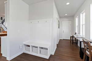 Mudroom with dark wood finished floors, built in cubbies and hooks, wainscoating and recessed lighting