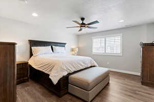 Primary bedroom featuring hardwood / wood-style floors, recessed lighting, a ceiling fan, and a textured ceiling