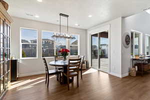 Dining area featuring hardwood / wood-style flooring, hanging lights, and a textured ceiling