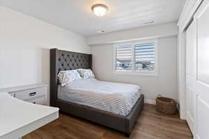 Guest bedroom featuring dark wood-style floors, a closet, and a textured ceiling