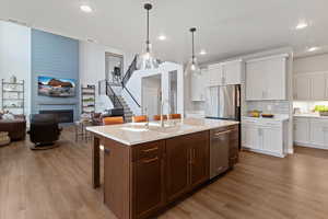 Kitchen with a breakfast bar area, open floor plan, two tone color scheme, pendant lighting, and light wood-type flooring