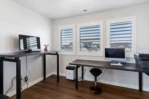 Home office behind french doors with dark wood finished floors and baseboards