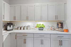 Butlers pantry with light stone counters and white cabinetry