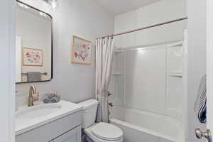Level 1 guest full bathroom featuring vanity and shower / tub combo with curtain