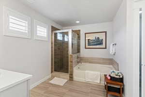 Full en-suite bathroom servicing primary bedroom with a shower stall, vanity, and a separate garden tub