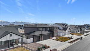 View of front of house featuring stone siding, a residential view, a vinyl gate, driveway, and a garage