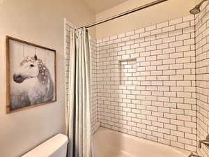 Bathroom with toilet and shower / tub combo with curtain