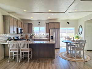 Kitchen with stainless steel appliances, a peninsula, a kitchen breakfast bar, light stone countertops, and recessed lighting