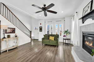 Living room featuring a tiled fireplace, wood finished floors, a ceiling fan, and recessed lighting