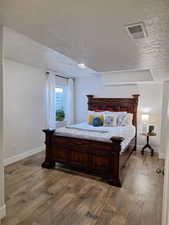 Bedroom with a textured ceiling and dark wood-style flooring