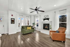Living room with a high end fireplace, dark wood finished floors, ceiling fan, and recessed lighting