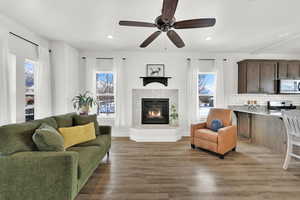 Living room with ceiling fan, light wood-style floors, recessed lighting, and a premium fireplace