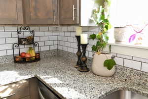 Kitchen featuring tasteful backsplash, light stone counters, and stainless steel dishwasher