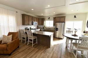 Kitchen with stainless steel appliances, a peninsula, a breakfast bar, dark stone counters, and dark wood finish cabinetry