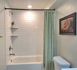 Bathroom featuring shower / tub combo, a textured ceiling, and recessed lighting