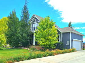 Obstructed view of property featuring a garage, a front yard, concrete driveway, and a shingled roof