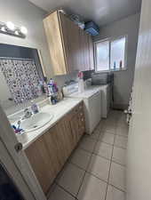 Laundry area featuring separate washer and dryer, light tile patterned floors, and a textured wall