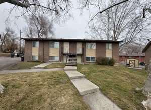 View of front facade featuring brick siding, a front lawn, and a storage unit