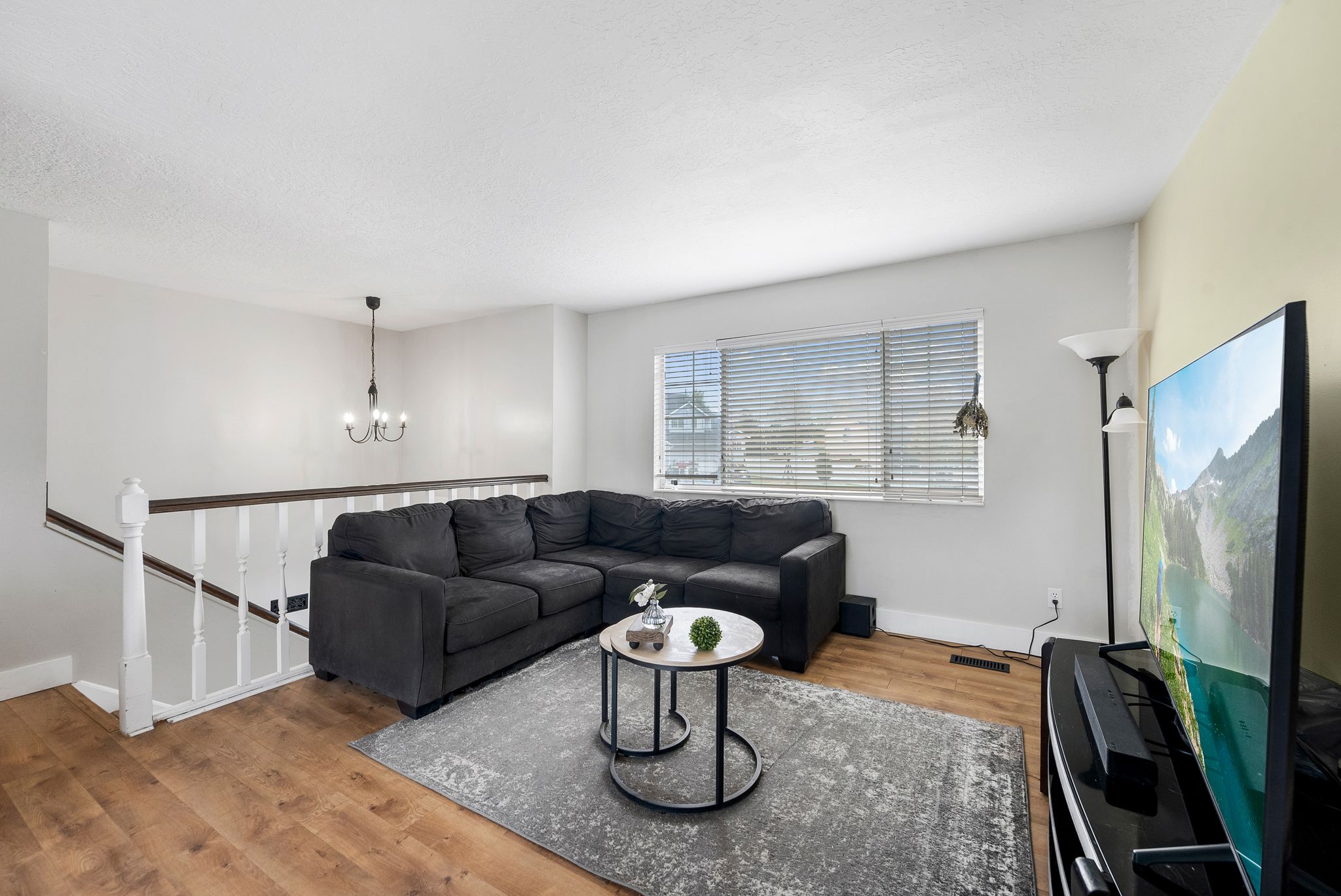 Living area with light wood-style flooring and suspended lighting