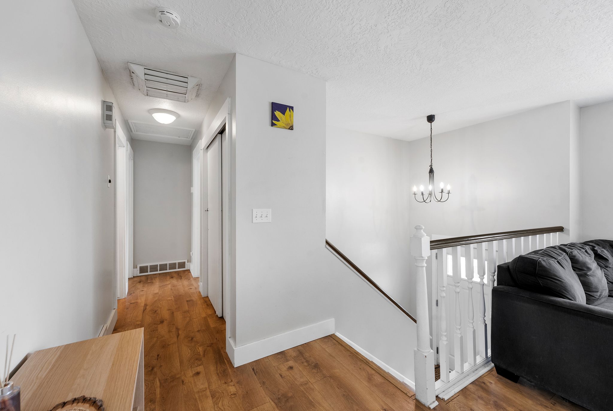 Corridor with an upstairs landing, hardwood / wood-style flooring, cooling unit, a textured ceiling, and suspended lighting
