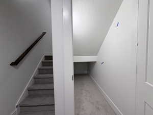 Stairs featuring a textured ceiling and carpet floors