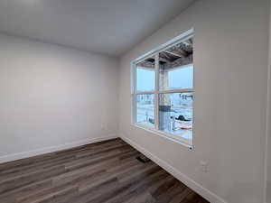 Empty room featuring dark wood-style flooring and baseboards
