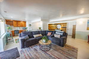 Living area featuring light wood finished floors, a textured ceiling, bar with sink, and recessed lighting