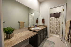 Full bathroom with vanity, a shower with shower curtain, and light wood-style floors