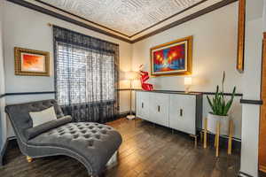 Sitting room with an ornate ceiling, crown molding, and dark wood-type flooring