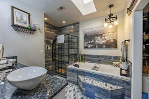 Bathroom with double vanity, a shower stall, a garden tub, and a skylight